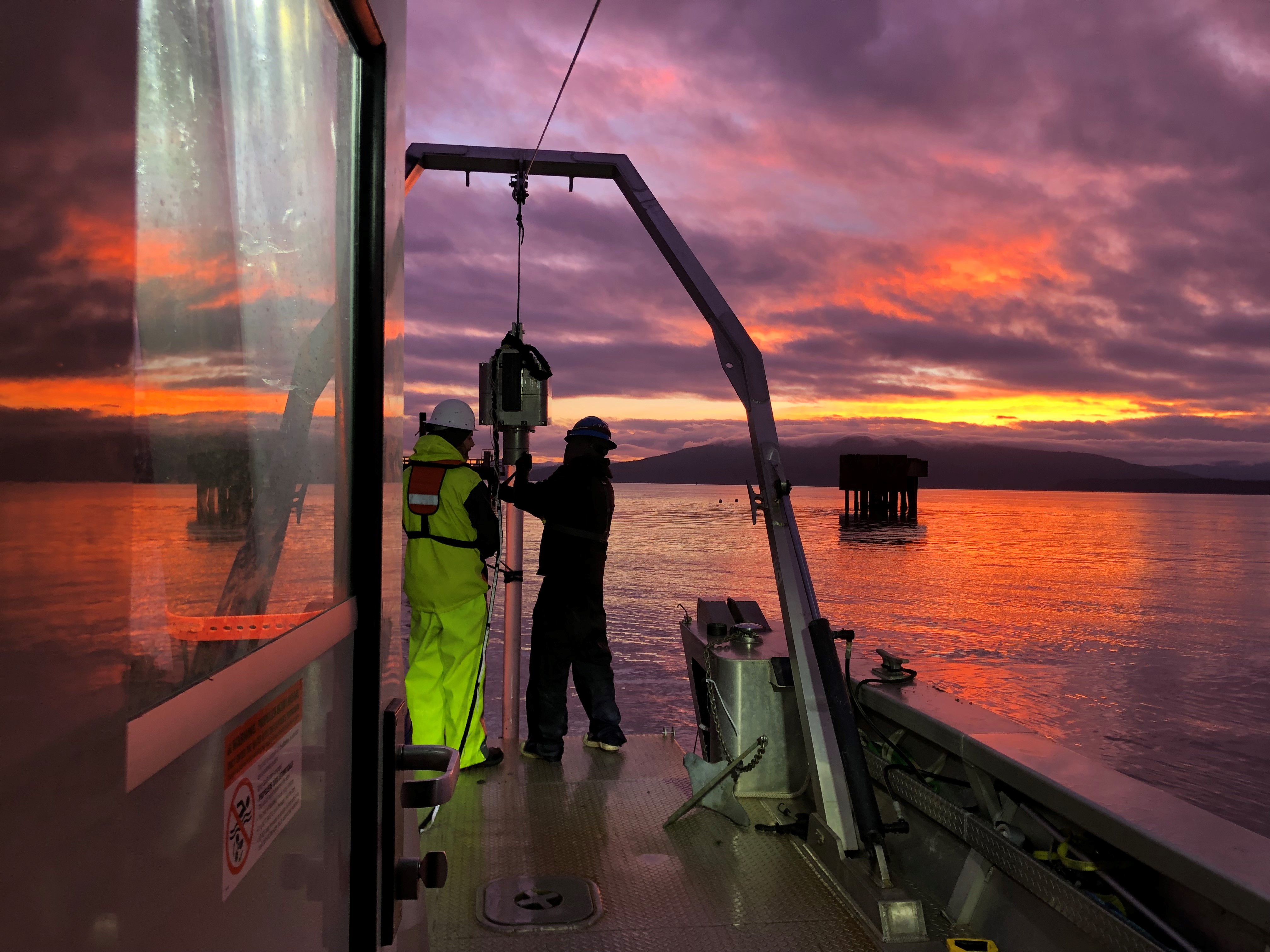 Crews on research boat working with equipment at sunset