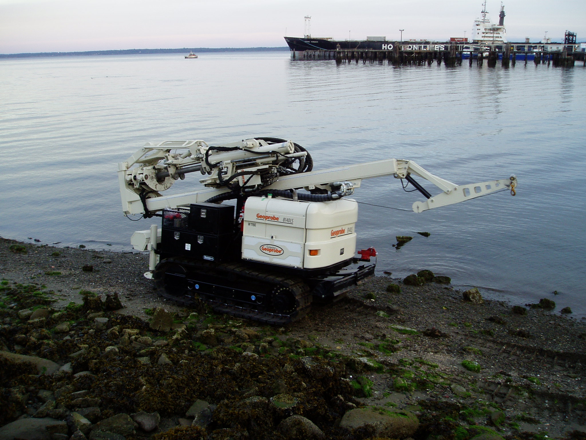 Sampling machine with arm on track treads on waterfront