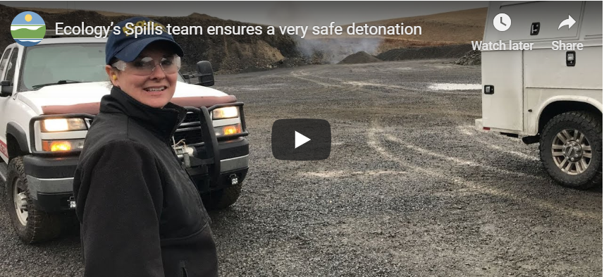 Screen shot of video. Female Ecology employee is candidly looking at the camera. A truck, gravel and hills are in the background. 
