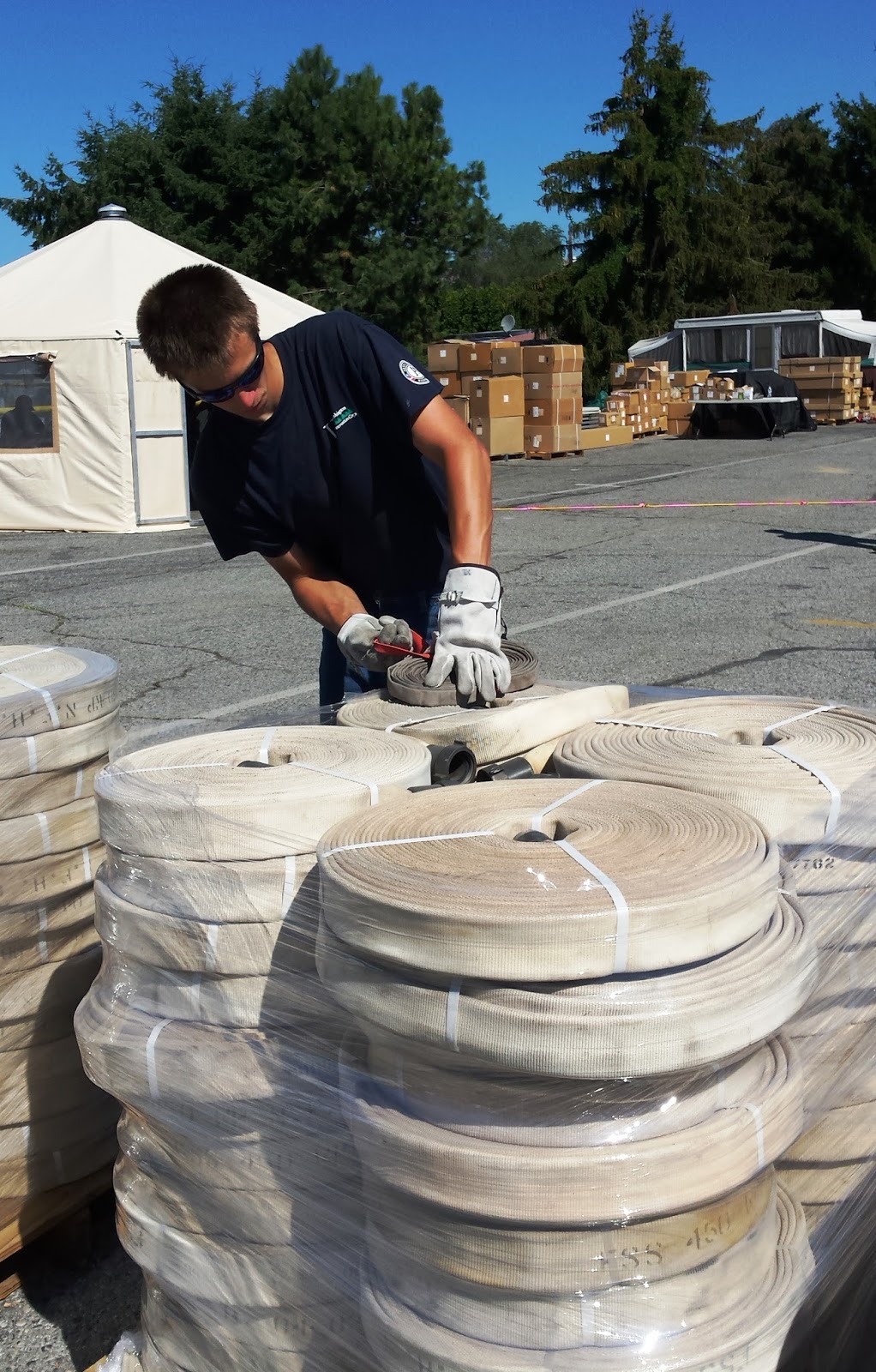 A WCC AmeriCorps member wraps fire hose in a thick, tall stack.