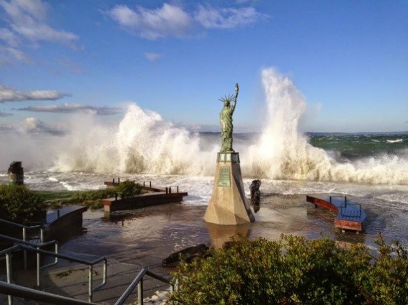 Small Statue of Liberty facing towards breaking waves at Alki Beach.