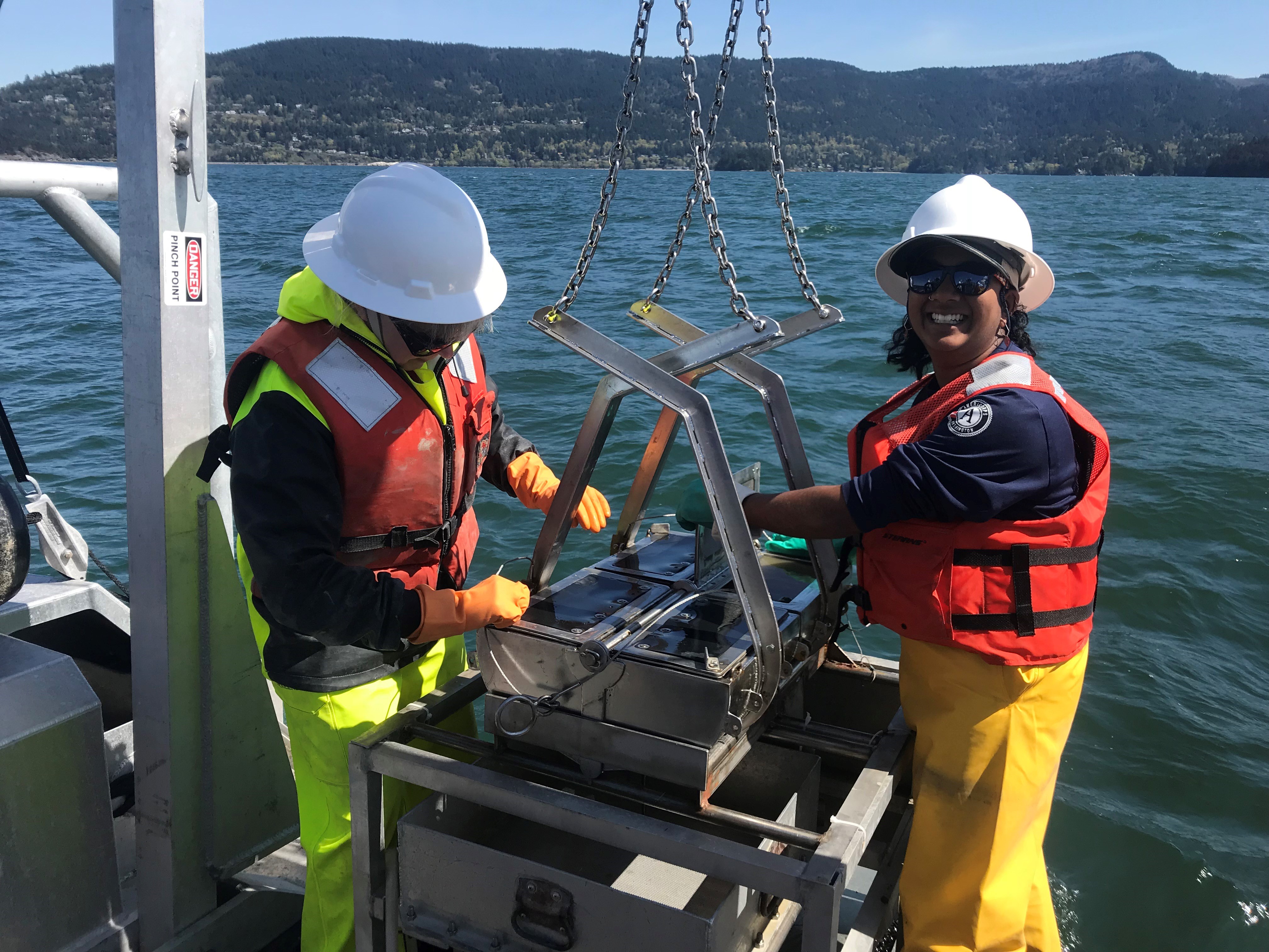 Former WCC Individual Placement member Juhi LaFuente and a colleague look at the sediment grab on a boat as part of a field project.