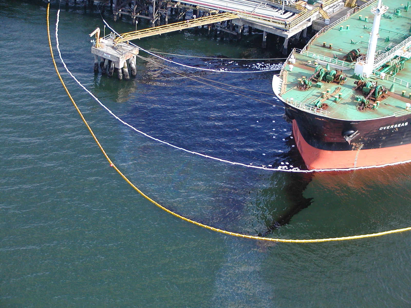 A vessel and dock with boom around oil in water
