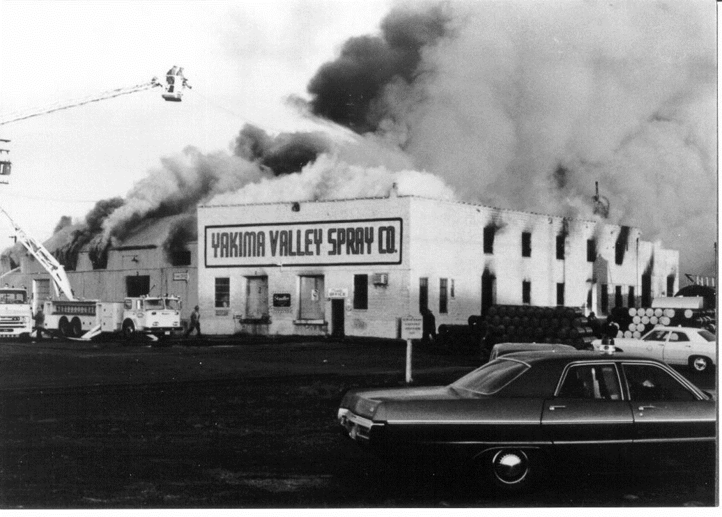 Fire crews with an extended ladder truck spray water onto the roof of an old building circa 1973