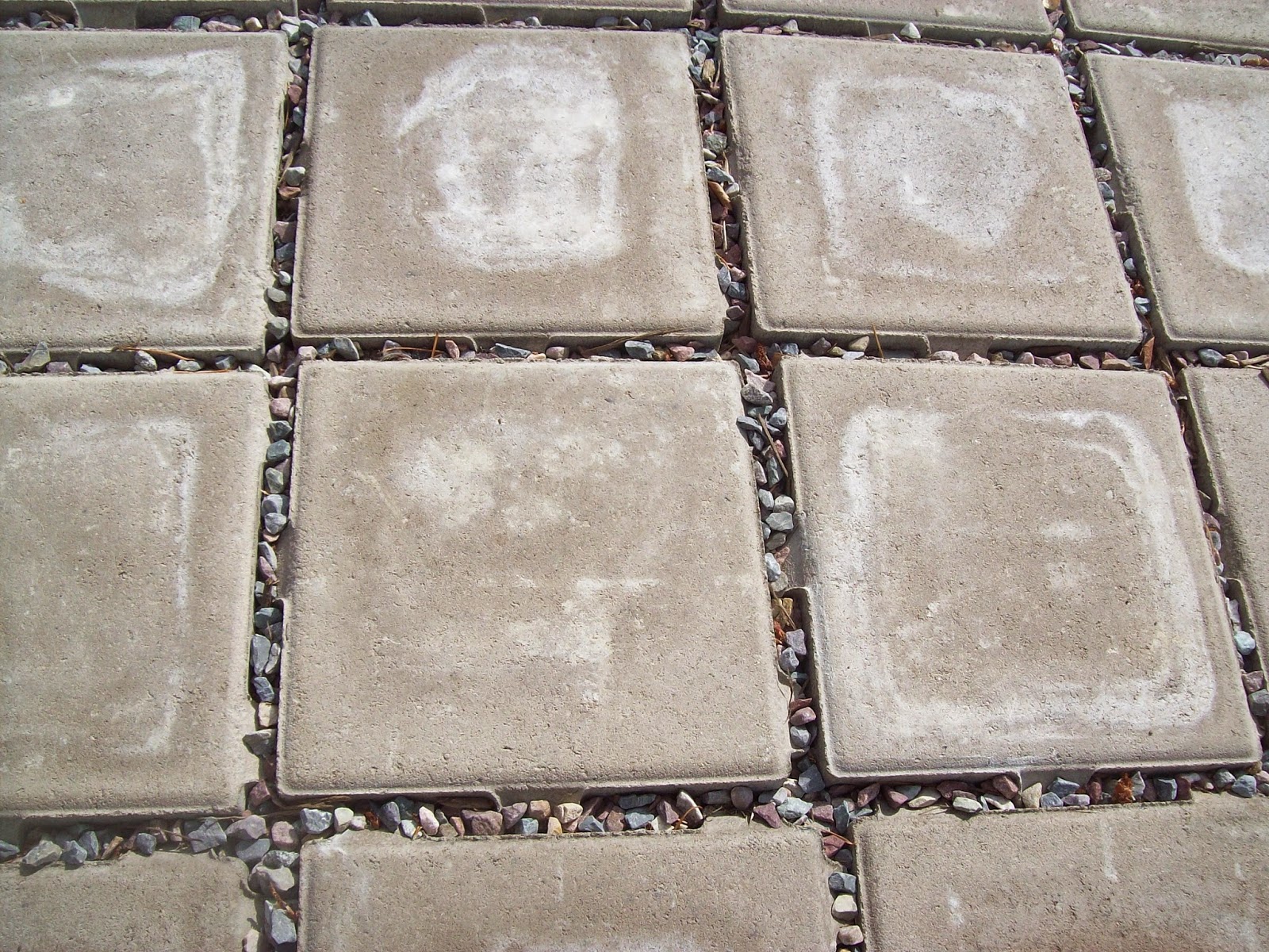 permeable patio tiles, a grayish tile, with small rocks in the cracks between tiles.