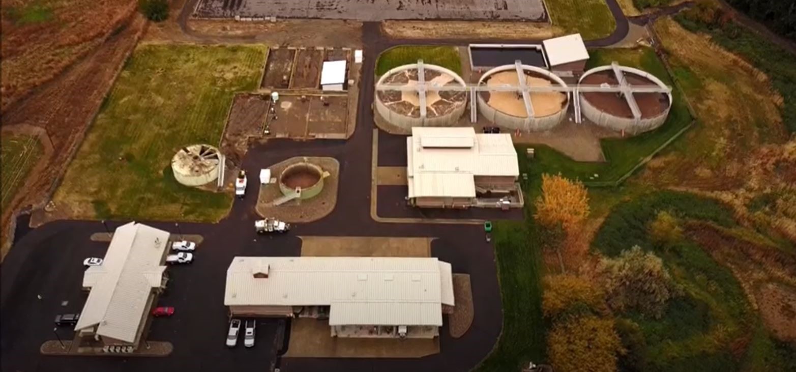 aerial view of wastewater treatment plant with lots of buildings and round holding tanks