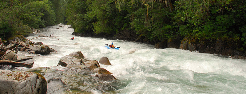 Three people kayaking down a rushing river