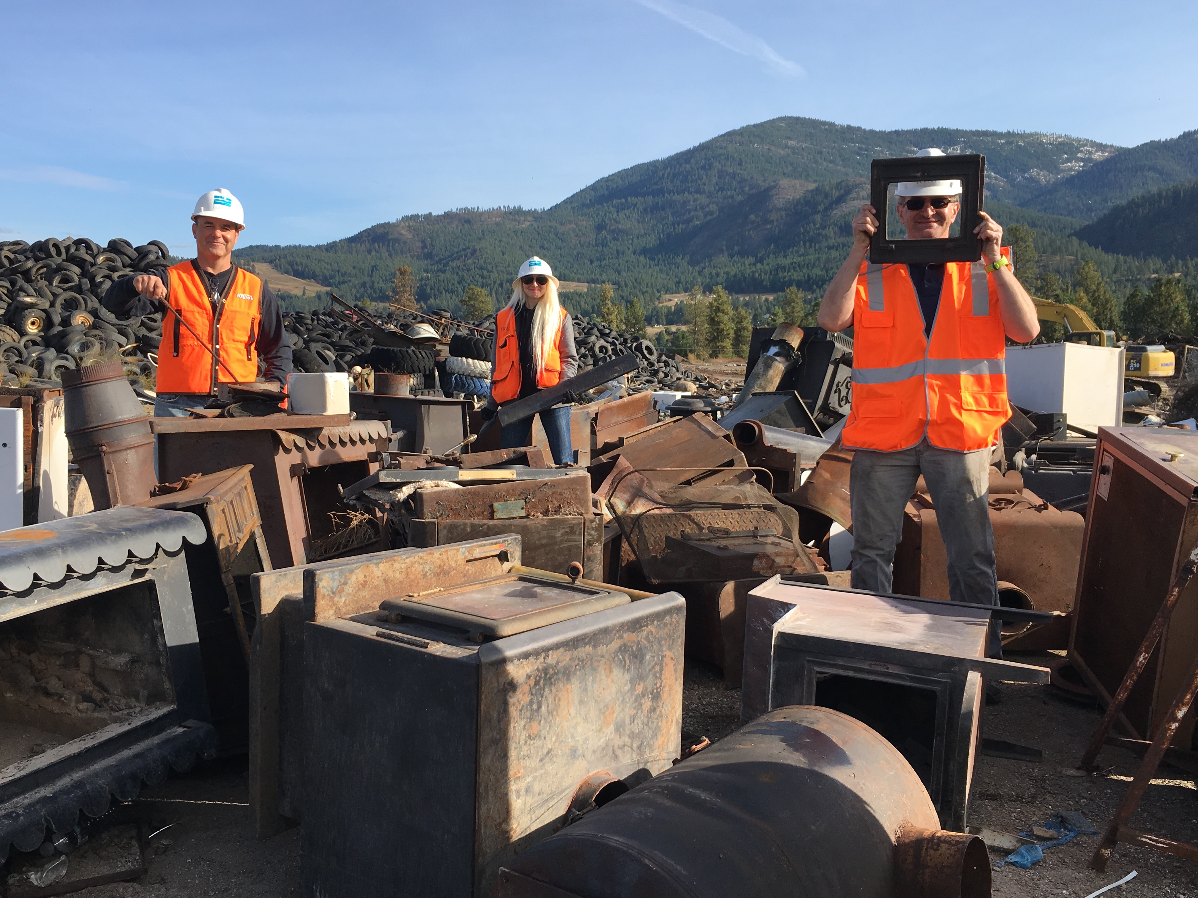 Ecology staff at the Stevens County Landfill with old wood stoves to be recycled
