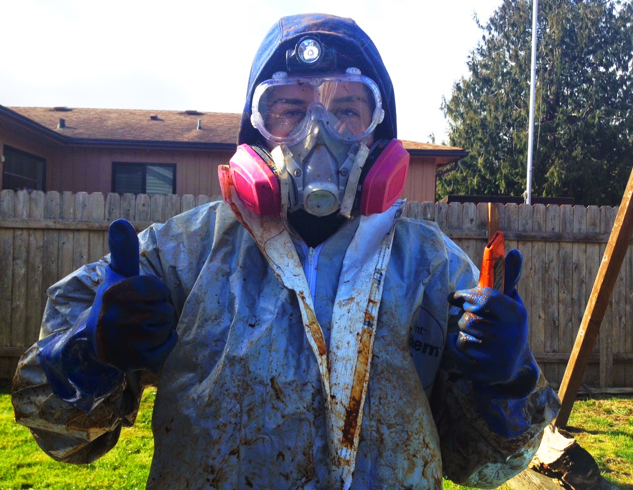 An AmeriCorps member wearing a respirator mask and a protective suit gives a "thumbs up" after a day in the field.