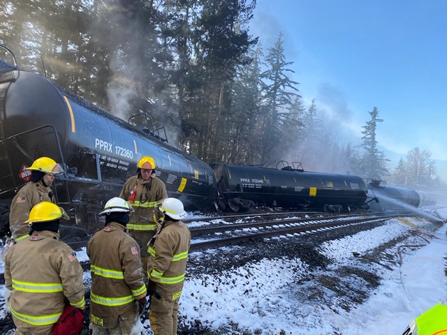 Firefighters standing in front of a derailed train