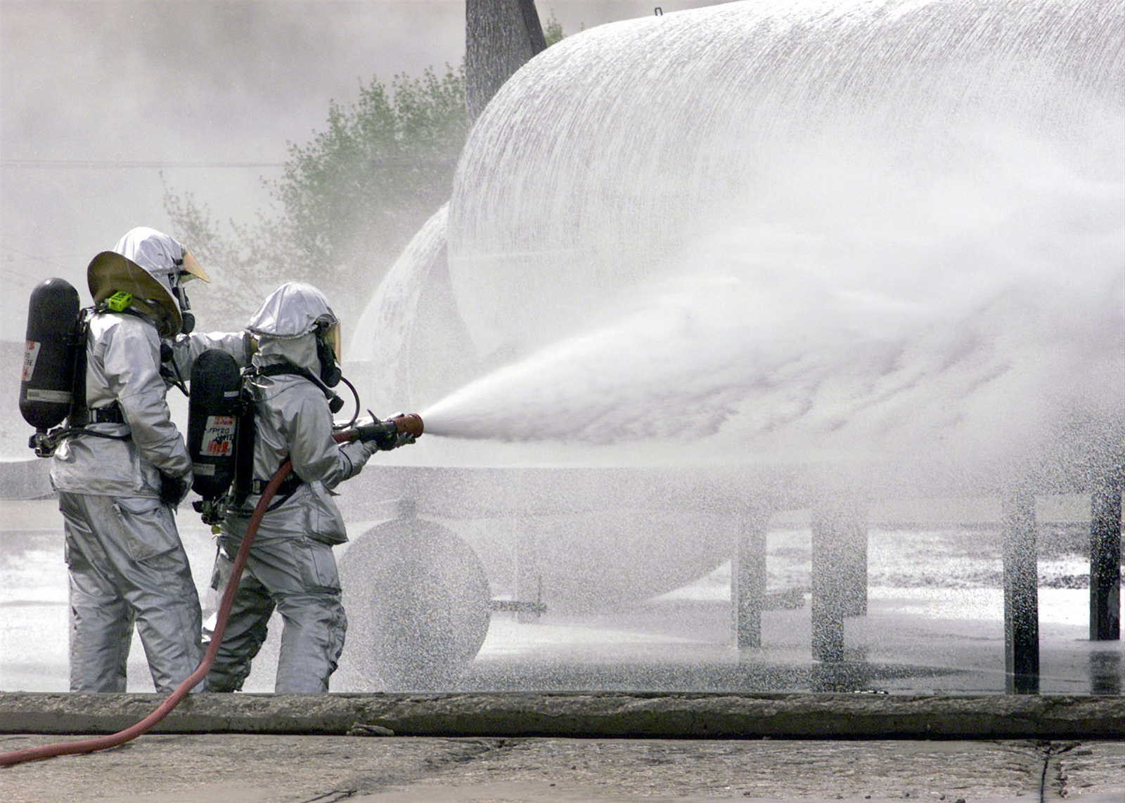 Fire fighters in protective gear spray foam
