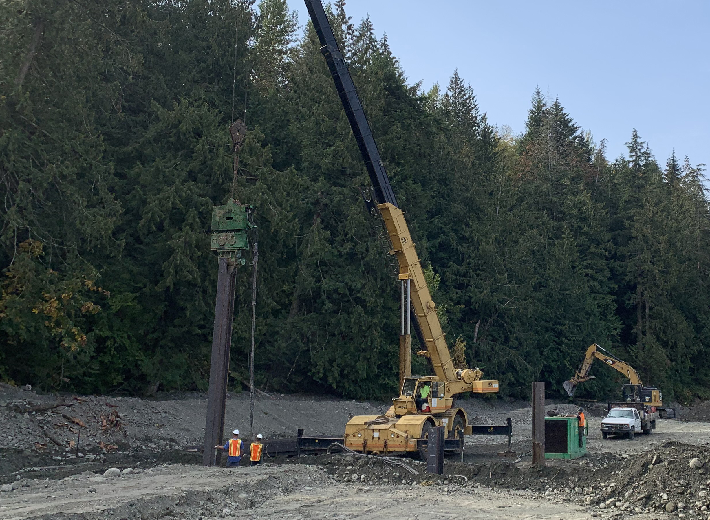 Workers use a crane and vibrating hammer to place a piling