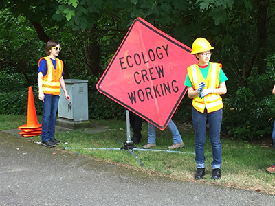A photo of Ecology Youth Corps working on the side of the road.