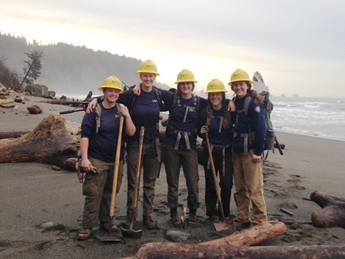 WCC work crew on a Washington beach holding tools.
