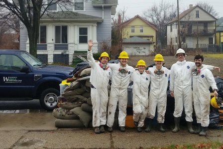 WCC AmeriCorps members stand near debris pile removed during the mucking and gutting of a home in Detroit, Michigan.