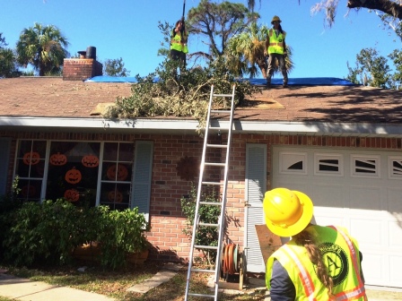 WCC AmeriCorps members remove branches threatening the roof of a Florida home.