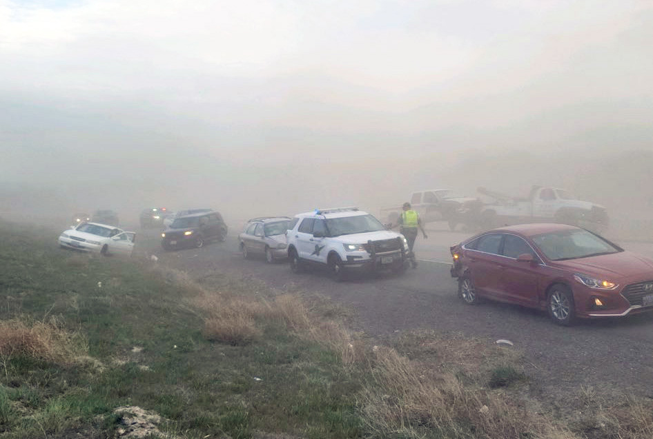 Multiple cars off the road and on the side of the road; a state patrol car in the center, lots of smoke and poor visibility.