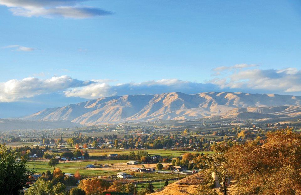 A photo of Yakima Valley featuring fields, mountains, trees, and houses