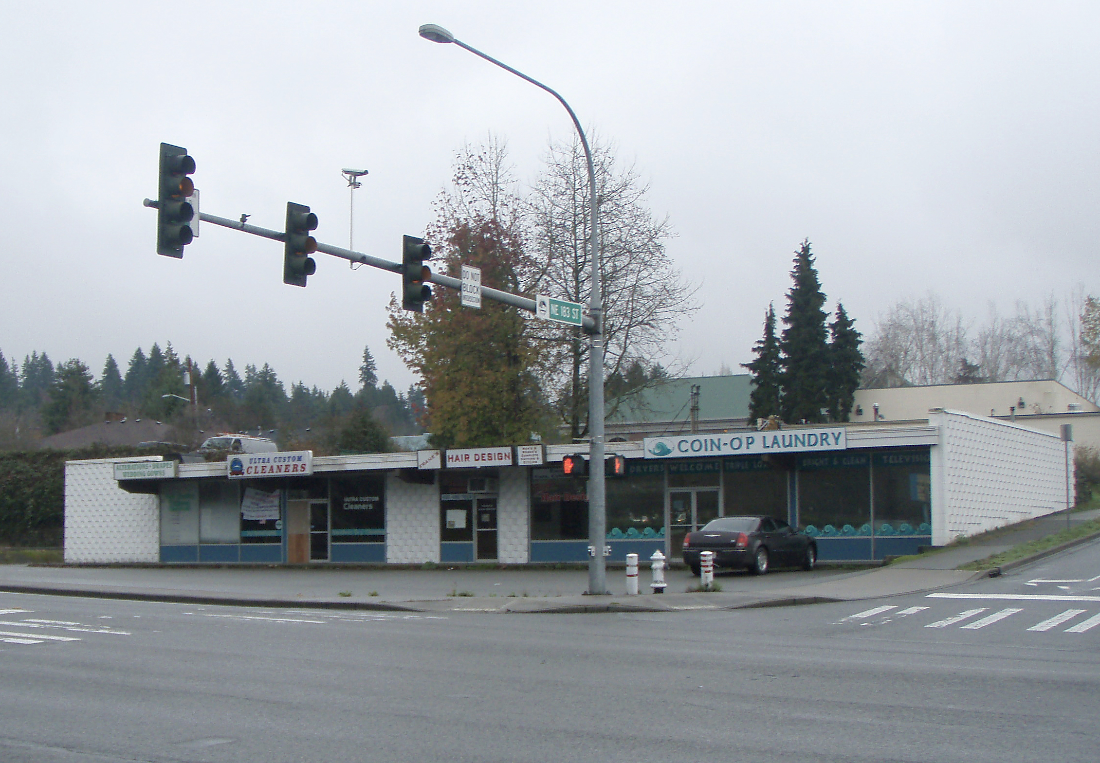 Old stripmall with dry cleaners, hair salon, and laundromat