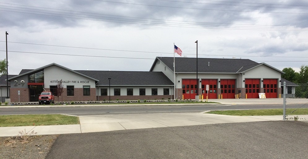 The Kittitas Valley Fire & Rescue district headquarters is a gray building with office space and garages with red doors for fire engines.