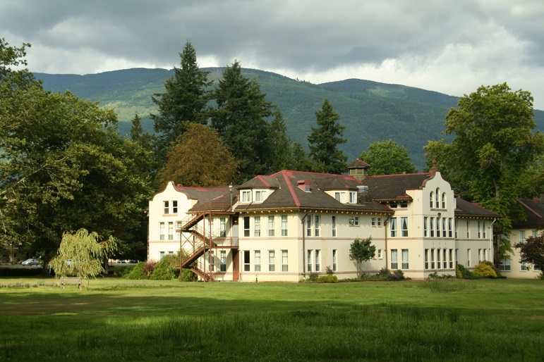 The historic Northern State Hospital sits on beautiful landscaped grounds with mountains in the background.