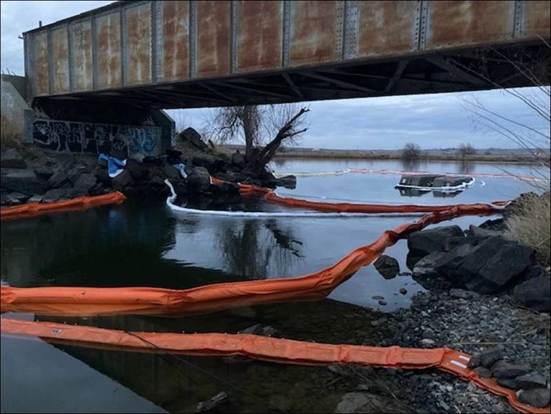 Capsized dredge by railroad bridge.