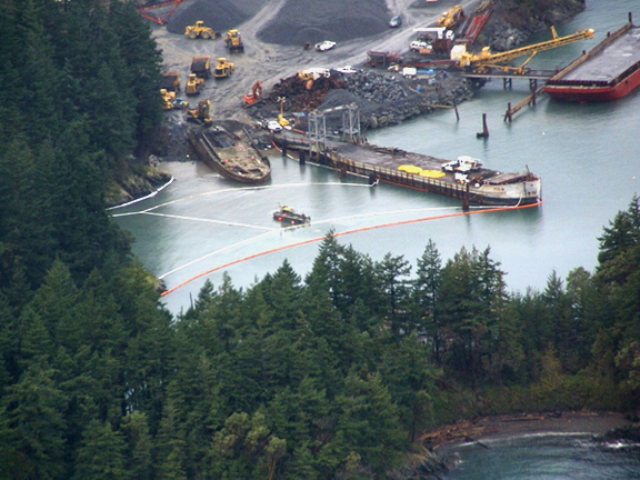 Lummi Rock quarry with a boom around the barge.