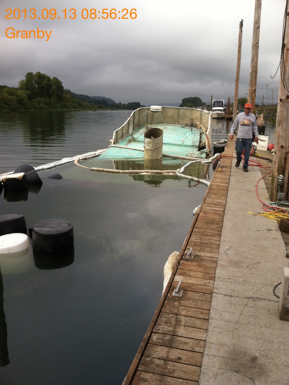 Sunken trawler surrounded by oil booms.