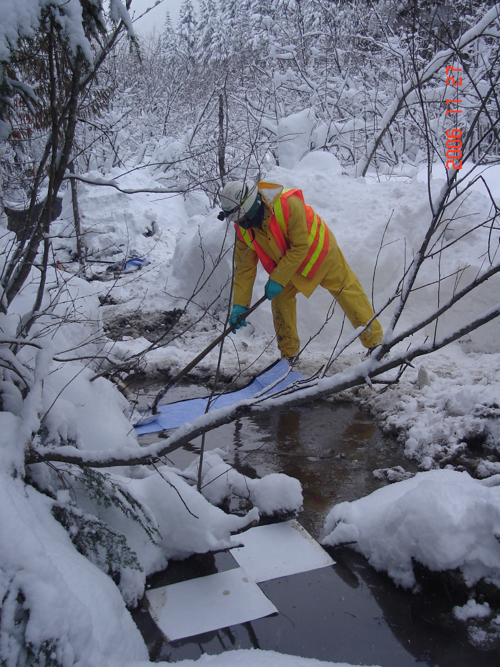 Worker placing pads to absorb diesel in a small stream that flows into Silver Creek.