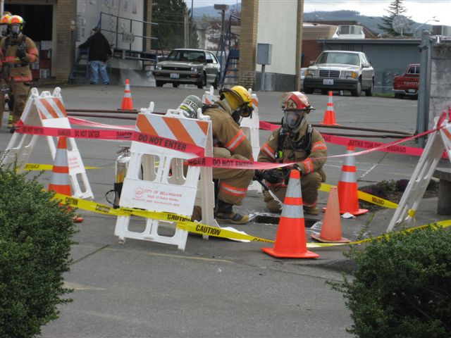 Bellingham firefighter spray foam into an area under an access cover where high concentrations of gasoline vapors created a risk for an explosion.