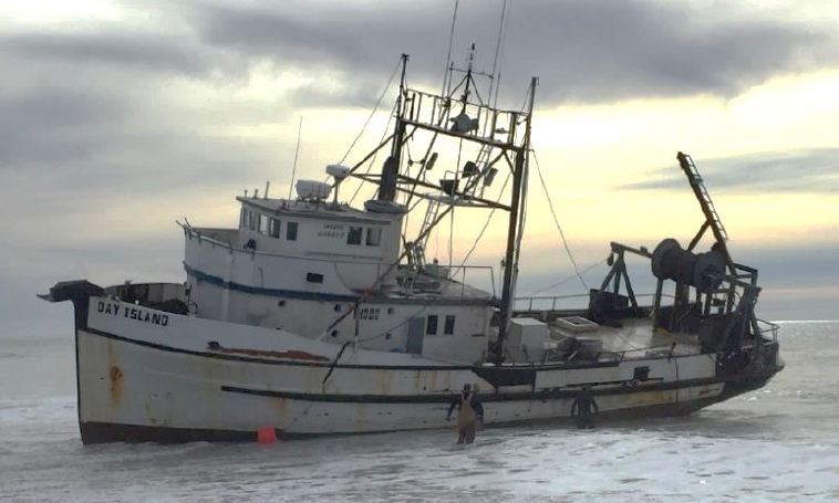 Fishing vessel DAY ISLAND aground on beach, listing to port.