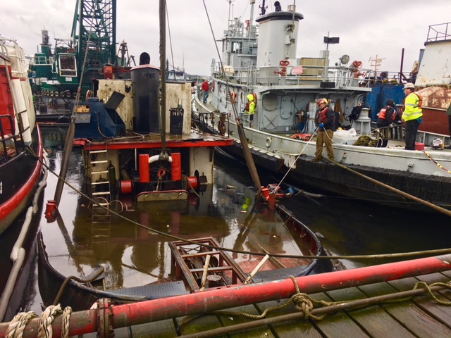 Old wooden tugboat being raised out of the water at a Seattle-area marina.