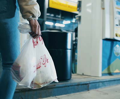 Imagen de una bolsa de comida rápida siendo tirada en la basura 