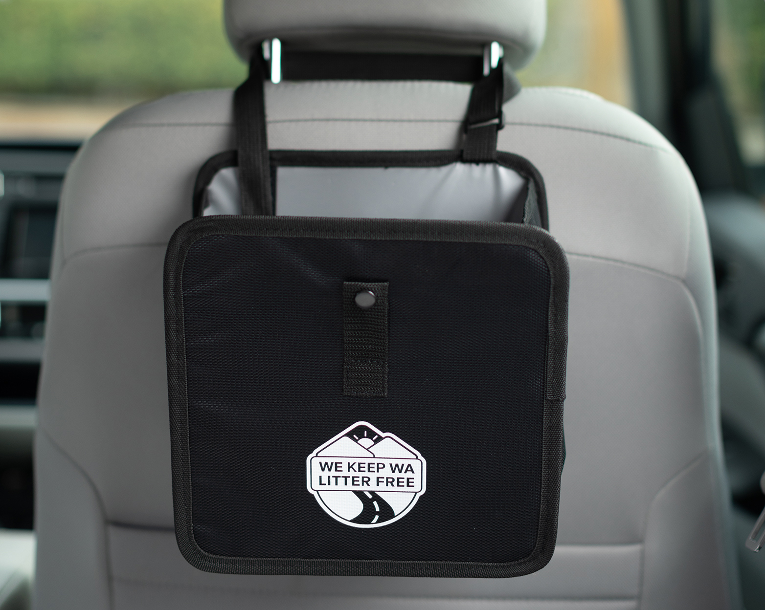 A vehicle litter bag slung around a passenger seat. Either fancy or plain, litter bags promote proper disposal of commonly littered items.