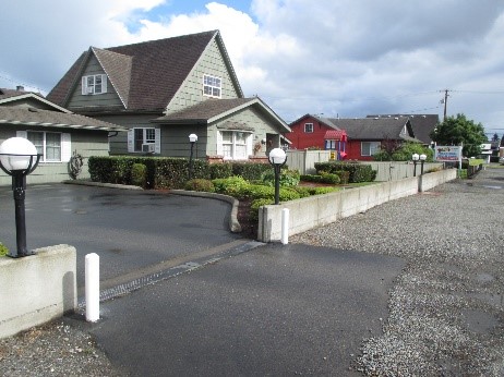 A home with a concrete flood wall surrounding the property and a gate that can be closed across the driveway.