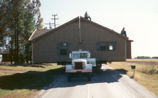 An entire house loaded on a truck being moved down a highway to a new location.