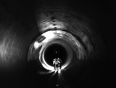 Inspectors walk through a 14-foot diameter underground concrete pipe that will convey irrigation water