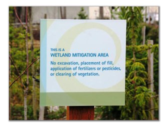 A sign identifying a wetland mitigation area that reads, "This is a wetland mitigation area. No excavation, placement of fill, application of fertilizers or pesticides, or clearing of vegetation." 