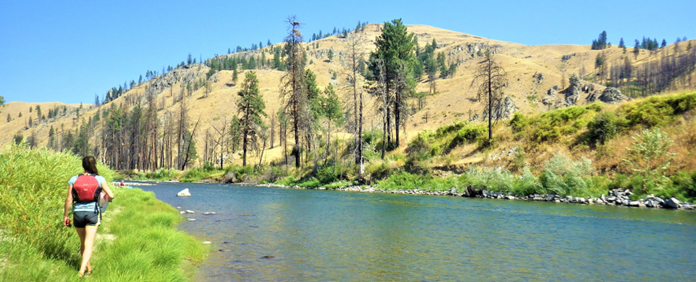 Photo showing crew member walk along side large river.