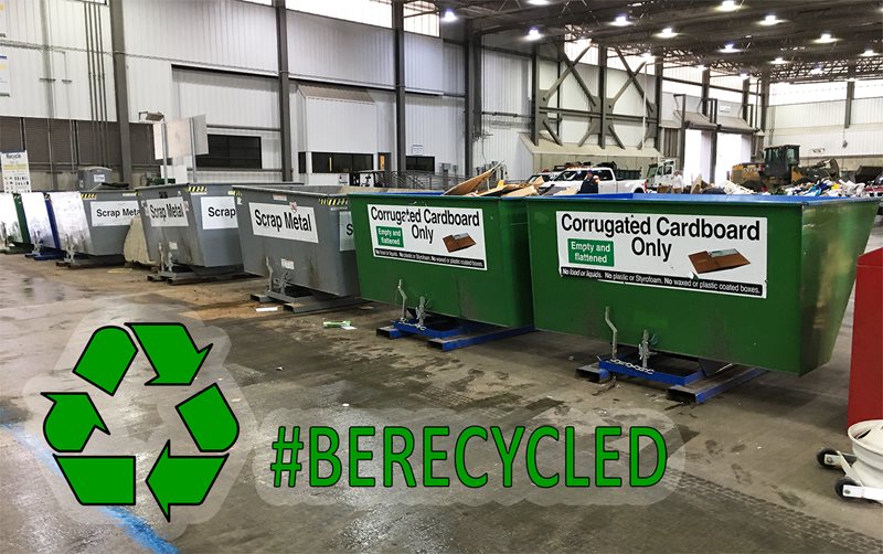 Bins full of recycled material line a King County transfer center floor. Text reading #BERECYCLED is overlaid.