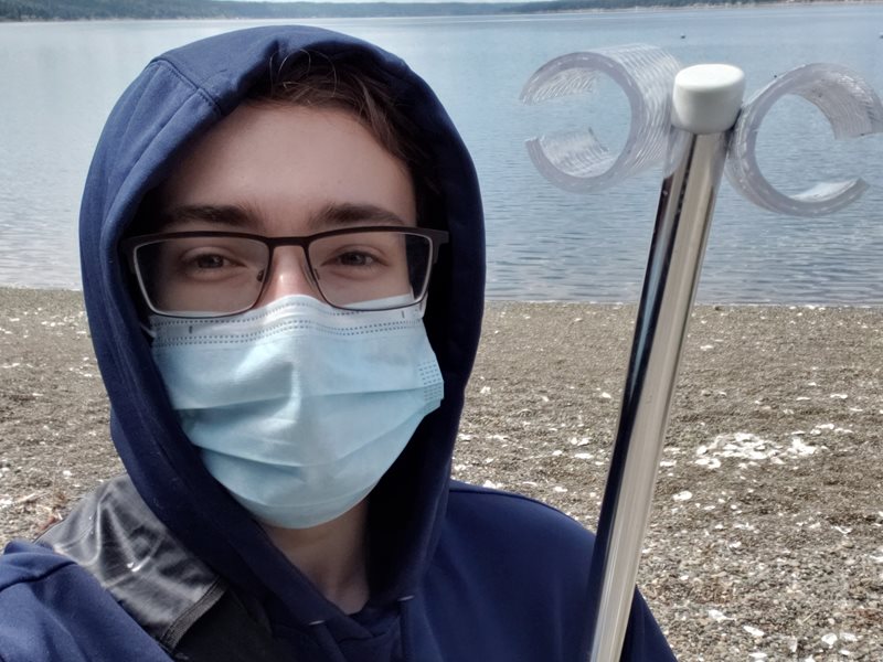 Head shot of Tyler Ransier wearing a mask and glasses holding water-sampling equipment 