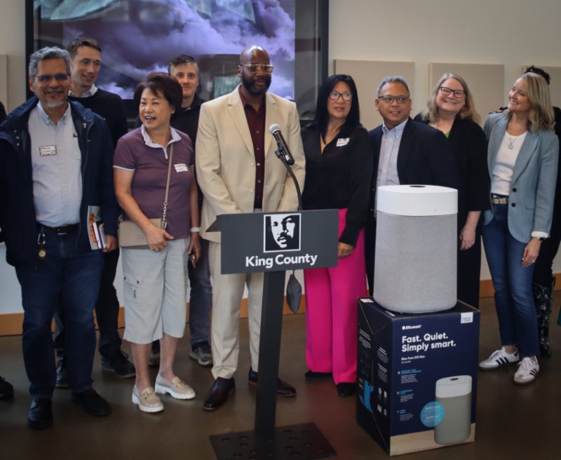 Community leaders and government workers pose behind an air purifier