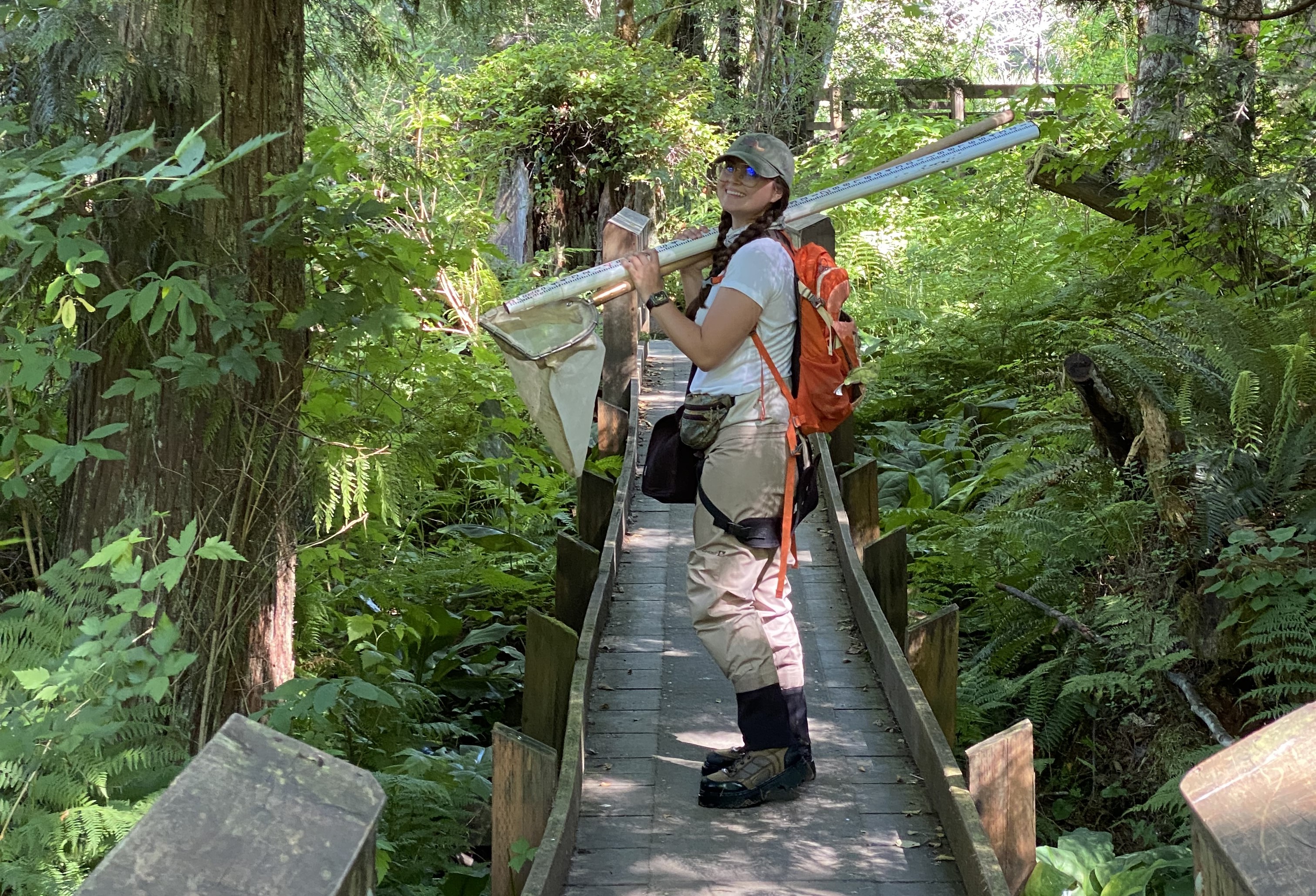 Scientist stands on footbridge with buckets of equipment