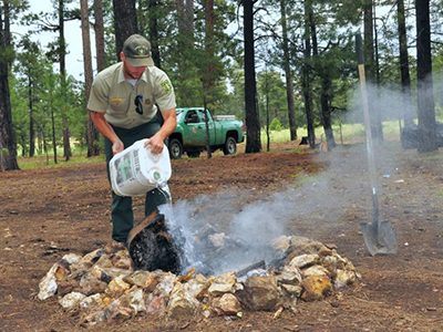 USFS employee extinguishing an abandoned campfire