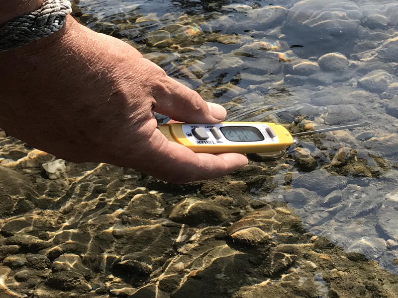 hand holding a thermometer in the water