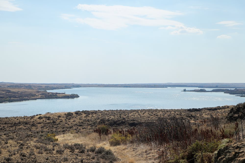 Sprague Lake in background with brown, rocky land in foreground. 