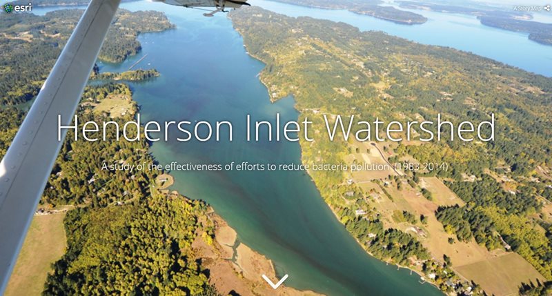 An aerial view of Henderson Inlet and surrounding land and woods. The overlaid text reads, "Henderson Inlet Watershed A study of the effectiveness of efforts to reduce bacteria pollution  (1983-2014) 