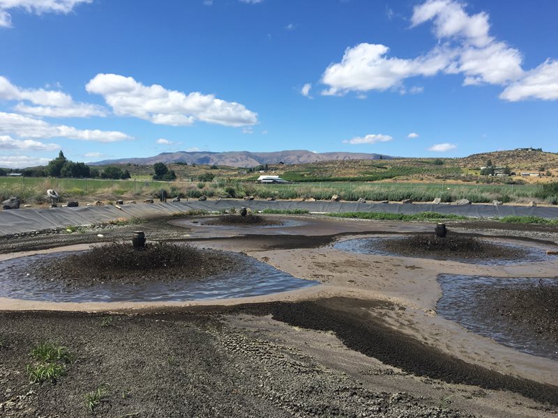 settling ponds at wastewater treatment plant with blue sky and hills in the background