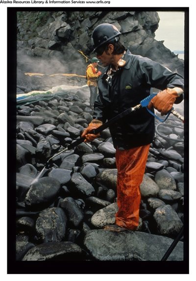 A response worker cleaning oil off a rock in Alaska. 