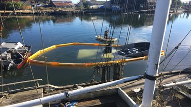a boat is submerged under the water and is surrounded by protective boom material